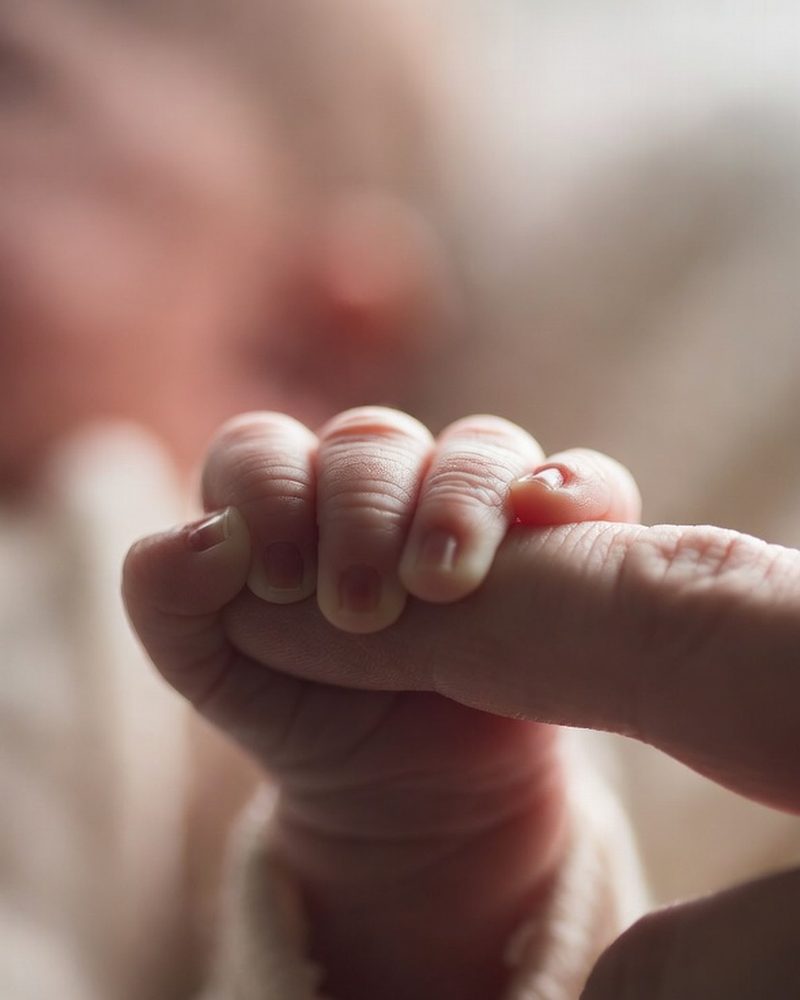 Vastasyntynyt vauva pitää kiinni aikuisen sormesta